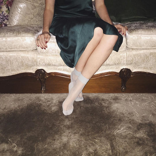Lady wearing emerald silk slip dress on couch 